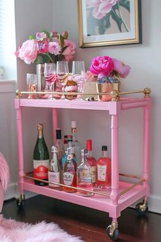 a pink bar cart filled with bottles and glasses