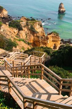 wooden steps lead down to the ocean near cliffs and water with rocks in the background