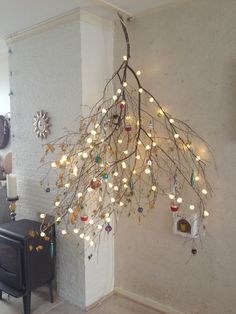 a tree with lights hanging from it's branches in front of a wall mounted clock