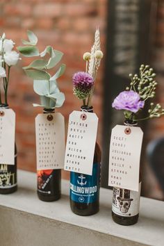 three bottles with flowers in them sitting on a window sill next to each other