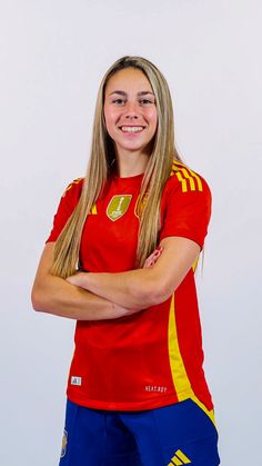 a woman in a red shirt and blue shorts posing for a photo with her arms crossed