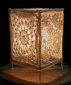 an intricately designed lamp is lit on a wooden stand with a black background in the middle