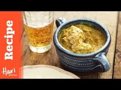 there is a bowl of food next to a glass of beer on the wooden table