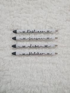 three pens with writing on them sitting next to each other in front of a white blanket