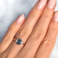 a woman's hand holding an engagement ring with a blue diamond in the middle