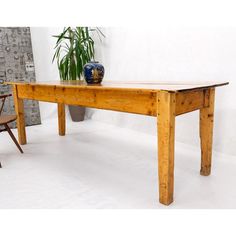 a wooden table sitting next to a chair and potted plant on top of it