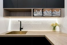 a kitchen with black cabinets and white tile backsplashing, two baskets on the wall