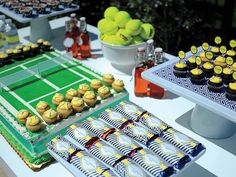 a table topped with lots of cupcakes next to a tennis court covered in yellow frosting