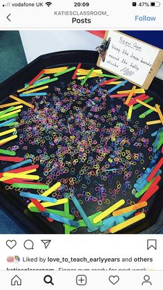 a black tray filled with lots of different colored plasticine sprinkles on top of a table