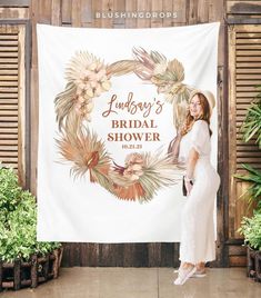 a woman standing in front of a bridal shower sign with flowers and leaves on it