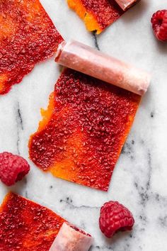 raspberries and other fruit on a marble counter top with one piece cut in half