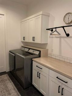 a washer and dryer in a room with white cupboards on the wall