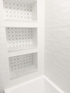 a white tiled bathroom with shelves above the bathtub