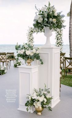 an outdoor ceremony setup with white flowers and greenery on the altar, overlooking the ocean