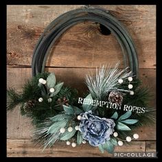 a wreath is hanging on the wall with pine cones and greenery in front of it