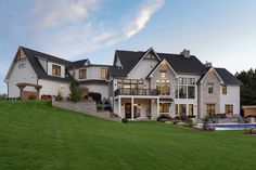 a large white house sitting on top of a lush green field next to a swimming pool