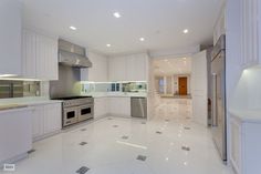 an empty kitchen with white cabinets and stainless steel appliances in the middle of the room