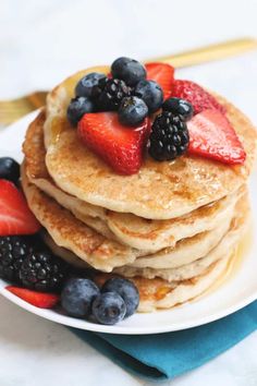 a stack of pancakes with berries and blueberries on top, sitting on a plate