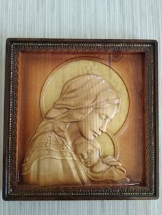 an image of the virgin mary holding a child in a wooden frame on a wall