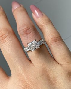 a woman's hand with two wedding rings on top of her ring and the middle finger