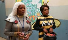 two women dressed in costumes standing next to each other and one is holding a cup