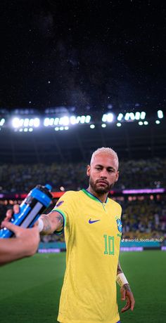 a man in yellow jersey standing on top of a soccer field