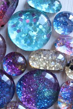 many different colored rocks on a wooden surface with some glitter in the middle and one is blue