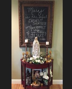 a table with flowers and candles on it in front of a chalkboard that says mary is the light