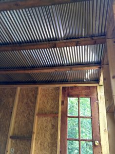 an open window in the side of a building with wooden walls and metal roofing