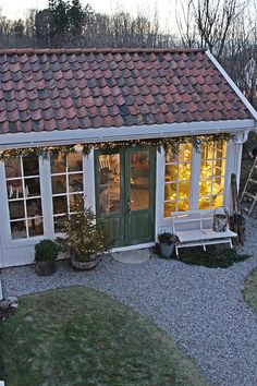 a small white house with lots of windows and lights on the roof is decorated for christmas