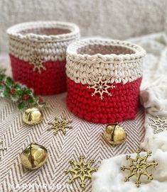 two crocheted baskets sitting on top of a blanket next to bells and christmas decorations