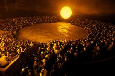 an aerial view of a circus ring at night with people in the middle and onlookers