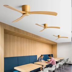 two people are sitting at a table in an office with blue booths and wooden ceiling fans