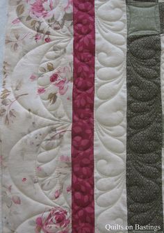 a close up of a quilt on a table cloth with pink and green flowers in the center