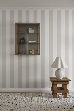 a room with striped walls and a wooden shelf on the wall next to a lamp