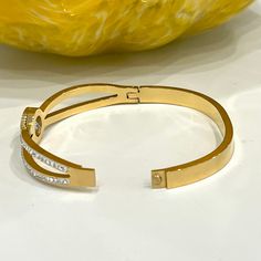 Simple yet luxurious, this gold roman numeral bangle bracelet looks astonishing on the wrist. The center of the bangle has a round flawless cubic zirconia stones with Roman numerals around them. Made of durable gold -toned stainless steel, the bracelet is hypoallergenic and water-resistant. The bracelet lasts daily use for years without losing its color or shine. - Stones Material: Cubic Zirconia.- Stones Shape: Round.- Metal: Stainless Steel.- Plating: 14K Gold plated.- Interior Diameter: 60 mm Modern Gold Cuff Bracelet With Cubic Zirconia, Gold Cuff Bracelet With Diamond Accents, Modern Gold Cubic Zirconia Cuff Bracelet, Roman Alphabet, Stainless Steel Plate, Roman Numeral, Gold Bangle Bracelet, Steel Plate, Roman Numerals