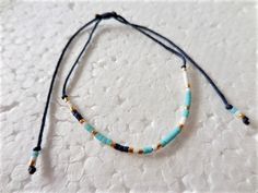 a blue and white beaded necklace with gold beads on a white tablecloth background