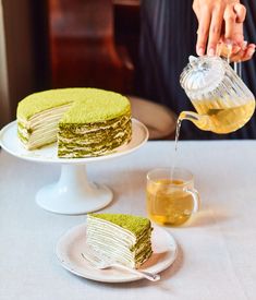 a person pouring tea into a cake on a plate with another piece cut in half