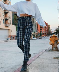 a person wearing plaid pants and a white shirt is walking down the sidewalk near a fire hydrant