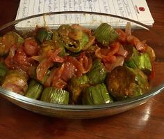 a metal bowl filled with cooked vegetables on top of a wooden table next to a piece of paper