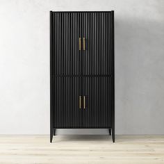 a tall black cabinet with two brass handles on the front and bottom, against a white wall