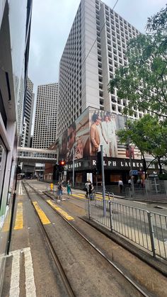 people are walking on the street in front of tall buildings with billboards above them