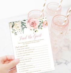 a baby shower game with pink flowers and gold straws on it, sitting next to some glasses