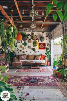 a living room filled with lots of plants and hanging pots on the wall next to a couch