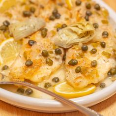 a white plate topped with fish covered in lemons and capers