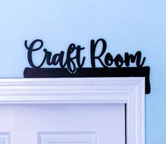 a black sign that says craft room on top of a white door with a blue wall in the background