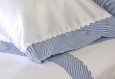 two pillows are stacked on top of each other with blue and white striped sheets in the background