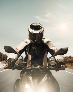 a person riding on the back of a motorcycle down a road with their hands in the air