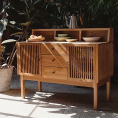 a wooden cabinet sitting next to a potted plant