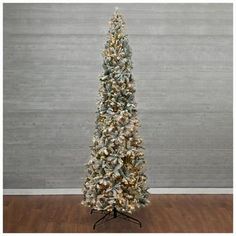 a small white christmas tree on a stand in front of a gray wall and wooden floor